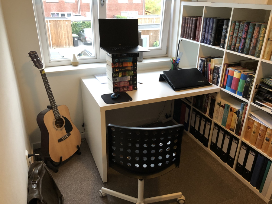 Setup on desk with a pile of books underneath the laptop