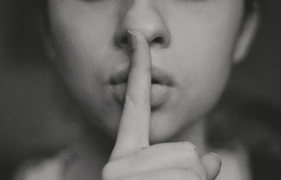 Photo of a woman holding her index finger to her mouth in a 'sst' manner